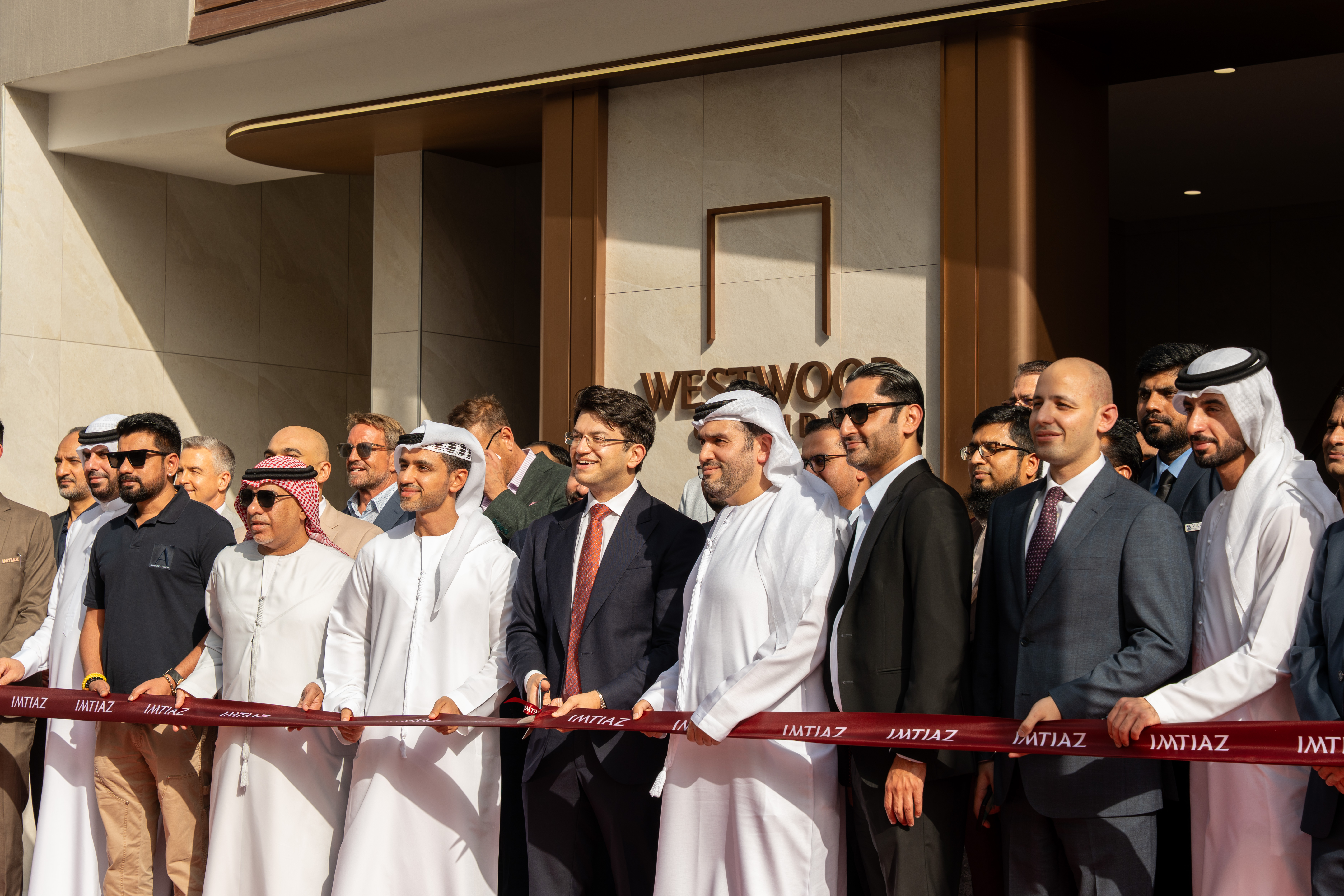 Events?Page=2 A group of people stands in front of the Westwood Grande II building, holding a ribbon for its opening ceremony.