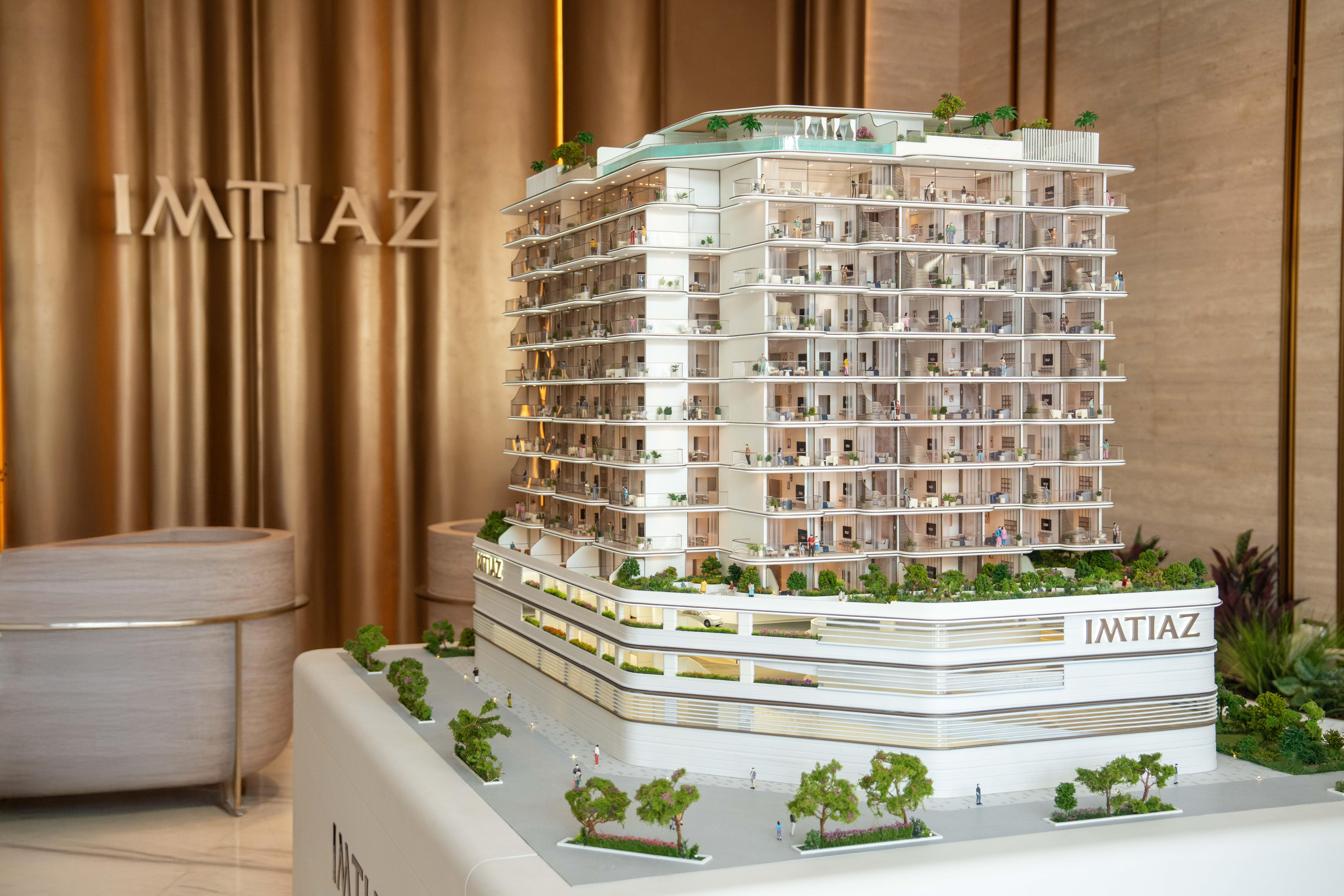 Events A detailed architectural model of a modern building with greenery, showcasing multiple floors and an IMTIAZ logo.