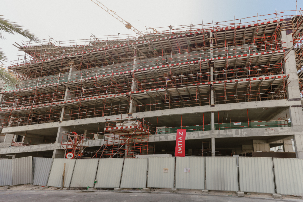 Pearl House By Imtiaz Construction site featuring a multi-story building with scaffolding, unfinished concrete walls, and safety barriers.