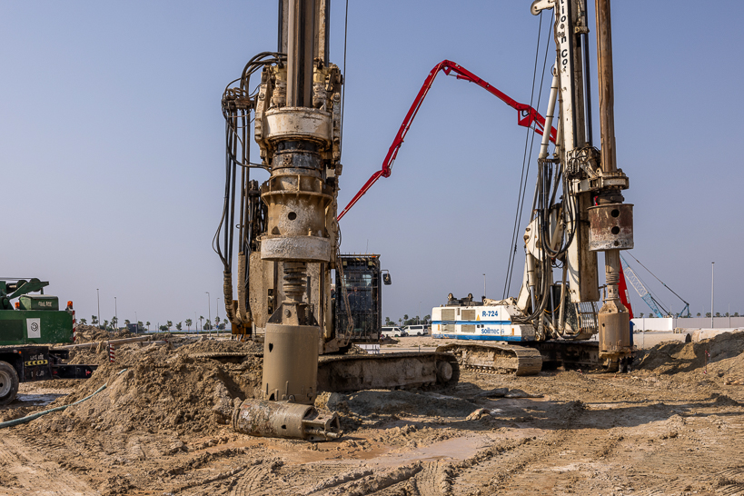 Beach Walk Residence Construction site featuring large drilling machines and equipment on sandy terrain against a clear sky.