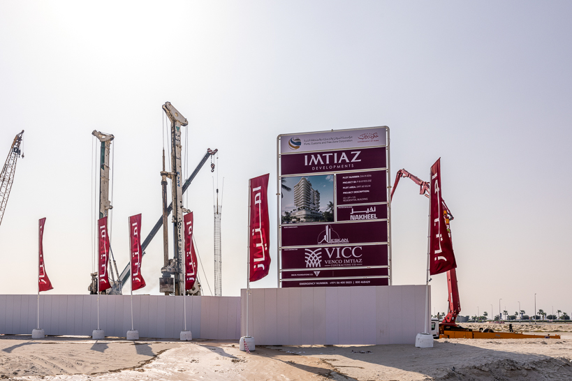 Beach Walk Residence A construction site featuring cranes, a sign for Imtiaz Developments, and banners in a clear sky.
