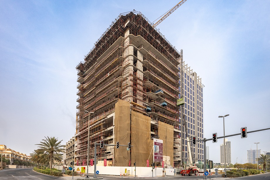 Pearl House By Imtiaz Construction site of a multi-story building with scaffolding, cranes, and nearby traffic signals on a clear day.