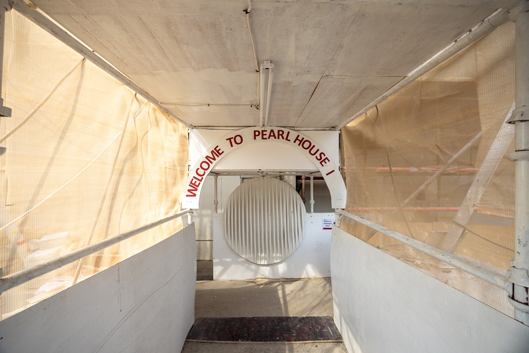 Pearl House By Imtiaz Entrance to Pearl House, featuring a curved sign and partially covered walkways with construction materials.