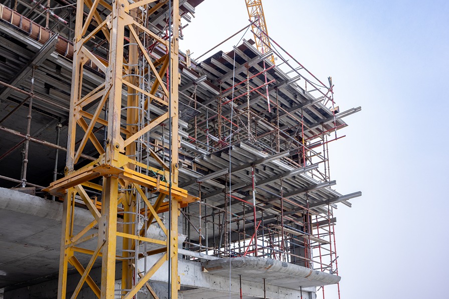 Pearl House By Imtiaz A construction site featuring a tall crane, scaffolding, and concrete structures under development against a blue sky.