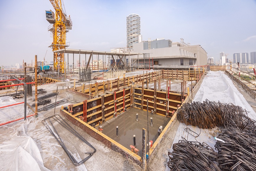 Pearl House By Imtiaz Construction site featuring a crane, unfinished structure, and a deep foundation pit with rebar and wooden formwork.