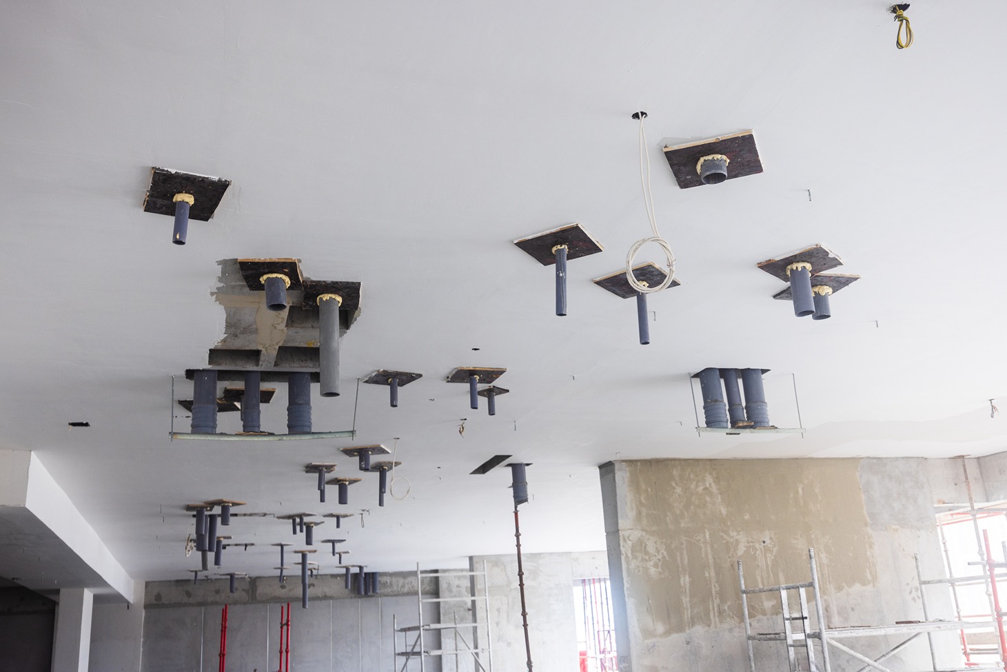 Pearl House By Imtiaz A view of an unfinished ceiling with protruding pipes and wooden bases, indicating construction work in progress.