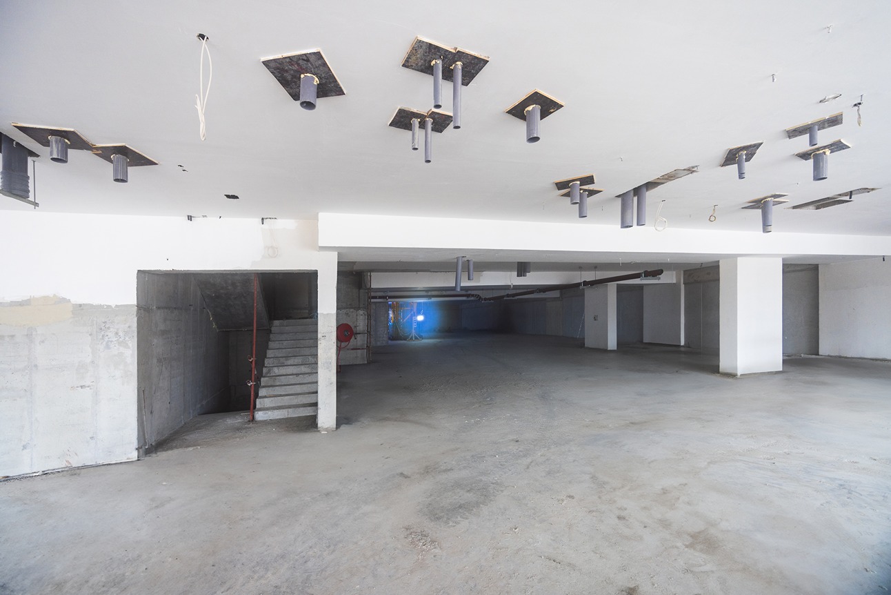 Pearl House By Imtiaz An empty, unfinished interior space with exposed ceilings, beams, and a staircase in the background.