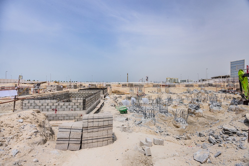 Beach Walk Residence Construction site with foundations, stacked blocks, and scaffolding under a clear blue sky.