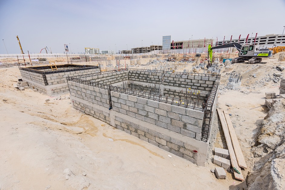 Beach Walk Residence Construction site with two concrete block foundations, surrounded by sand and construction materials.