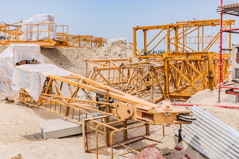 Beach Walk Residence Construction site featuring yellow cranes and scaffolding amidst sandy terrain under a clear blue sky.