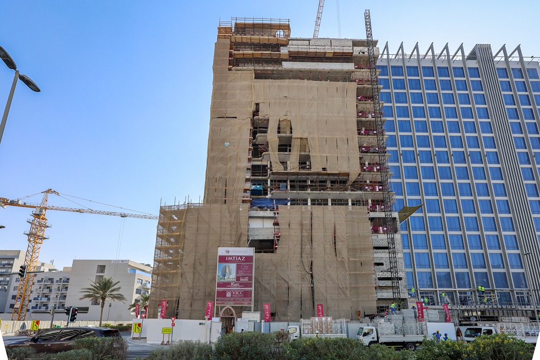 Pearl House By Imtiaz A partially constructed building covered in scaffolding and mesh, with cranes and workers visible nearby.