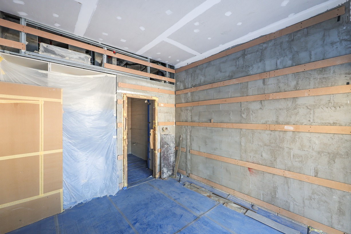 Pearl House By Imtiaz A partially constructed room with exposed concrete walls, wooden framing, and blue protective flooring.