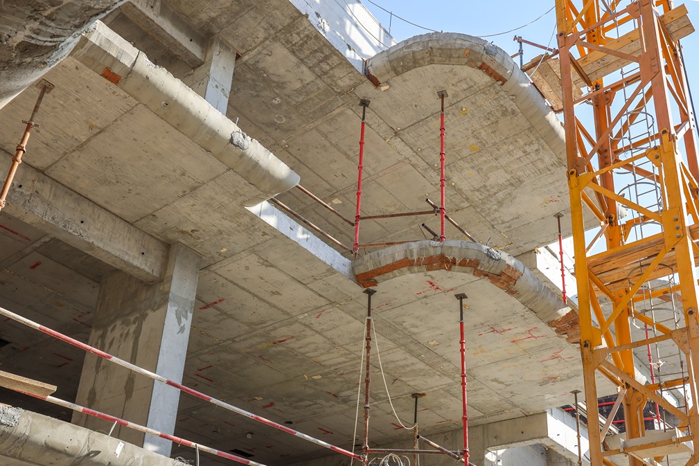 Pearl House By Imtiaz Construction site featuring concrete beams and scaffolding, with a crane visible against a clear sky.