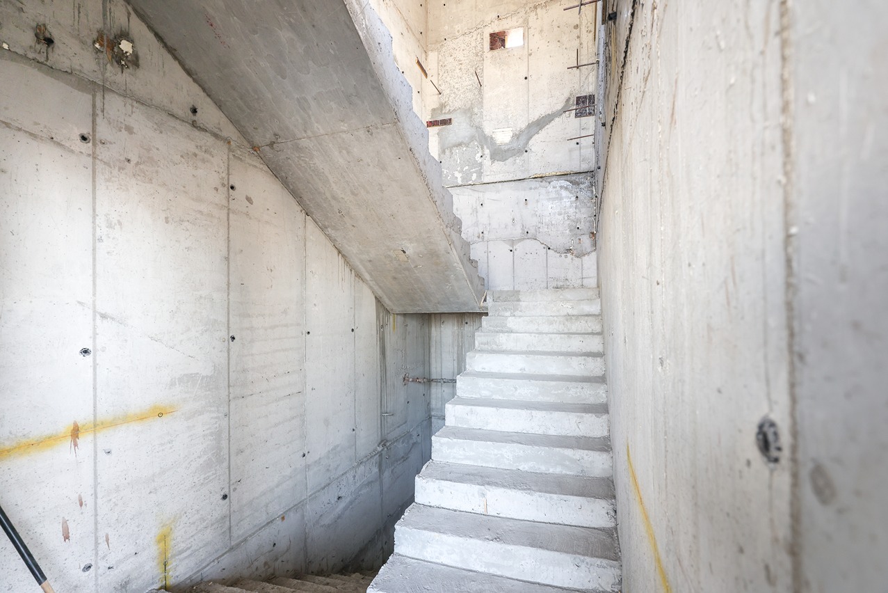 Pearl House By Imtiaz Interior view of a concrete stairwell under construction, featuring unfinished walls and exposed concrete surfaces.