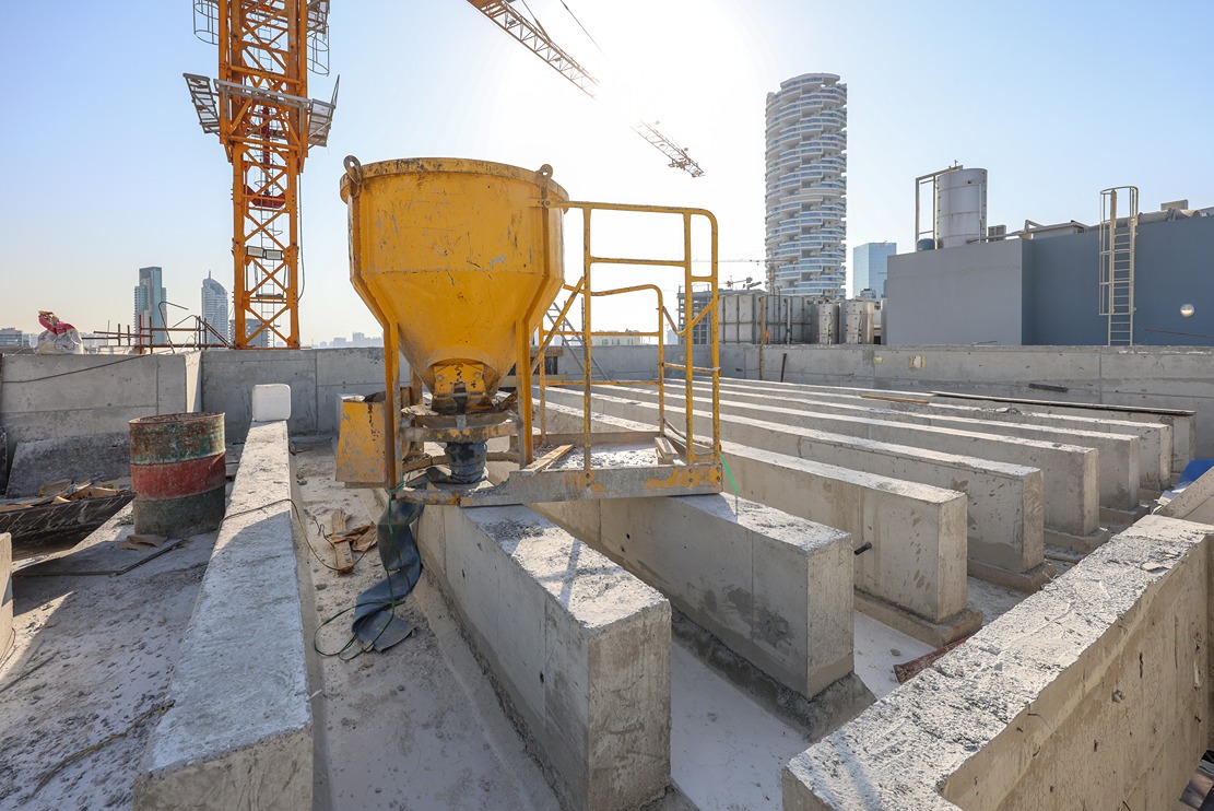 Pearl House By Imtiaz Construction site featuring a yellow concrete mixer, scaffolding, and concrete beams under a clear sky.