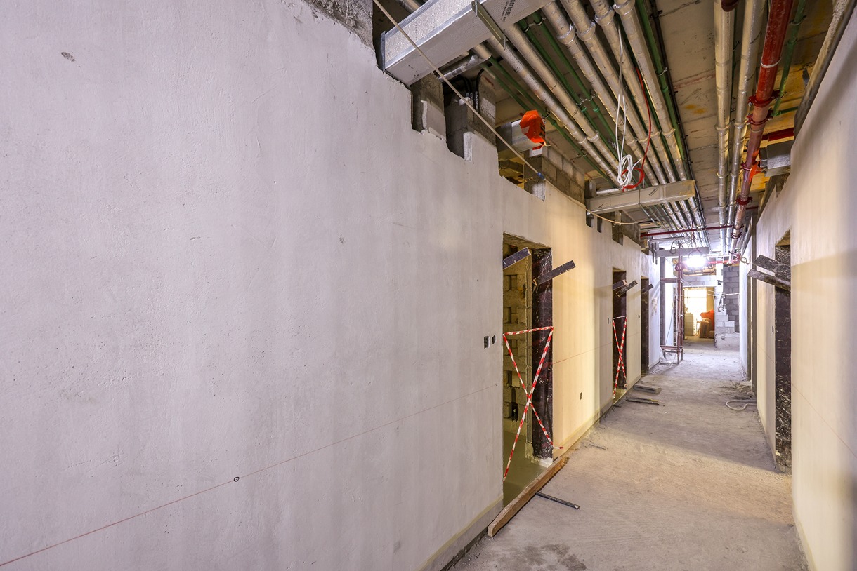 Pearl House By Imtiaz A partially constructed hallway with unfinished walls, exposed pipes, and construction barriers on doorways.