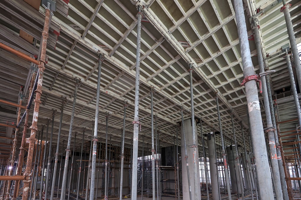 Beach Walk Residence A view of a construction site featuring scaffolding and concrete pillars supporting an unfinished ceiling structure.