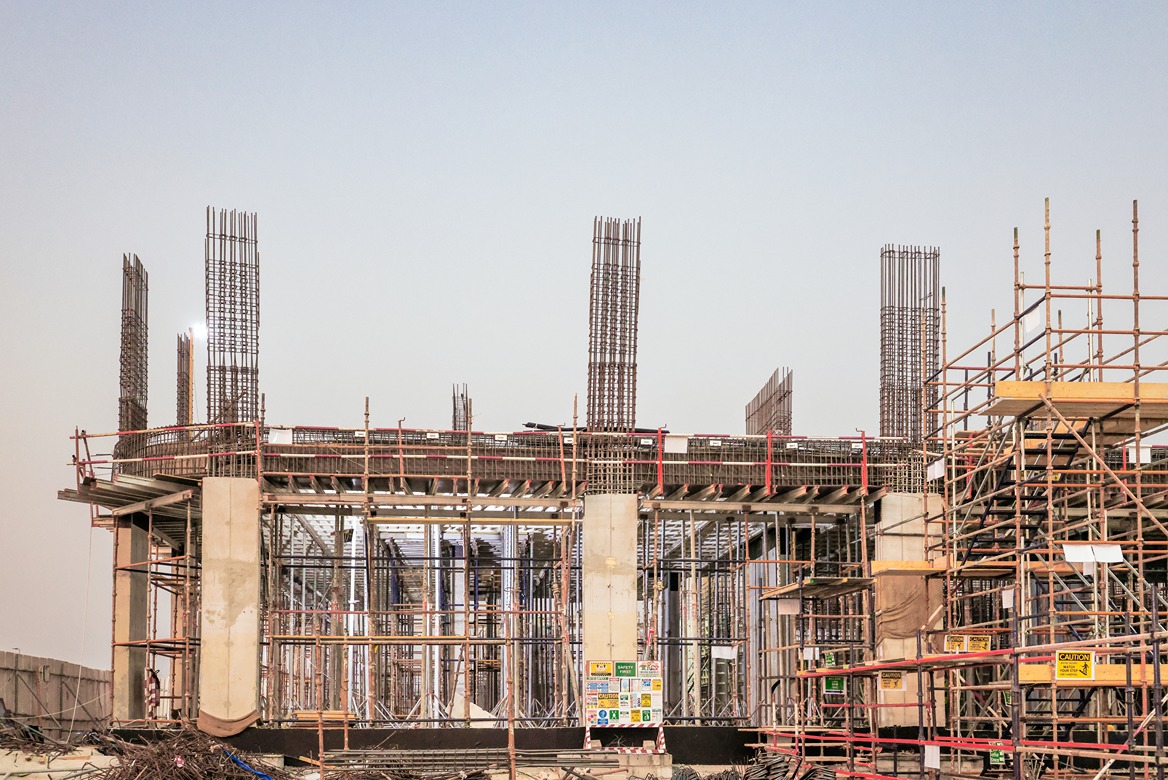 Beach Walk Residence A construction site featuring steel reinforcements, scaffolding, and concrete structures under a clear sky.