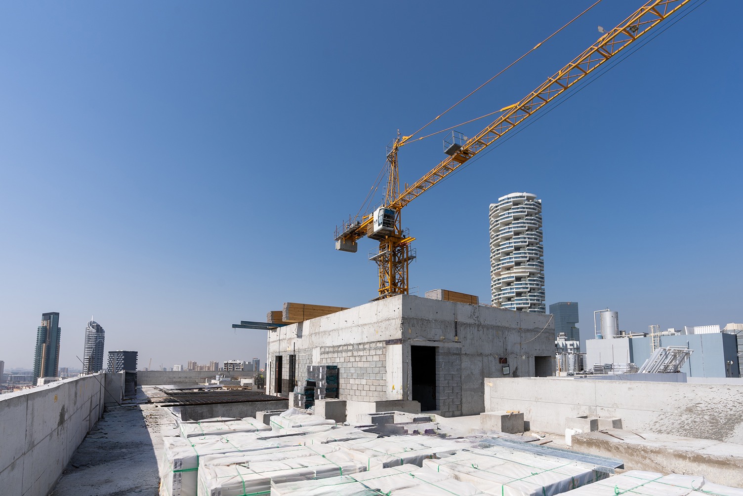 Pearl House By Imtiaz Construction site featuring a crane, concrete structures, and modern buildings against a clear blue sky.