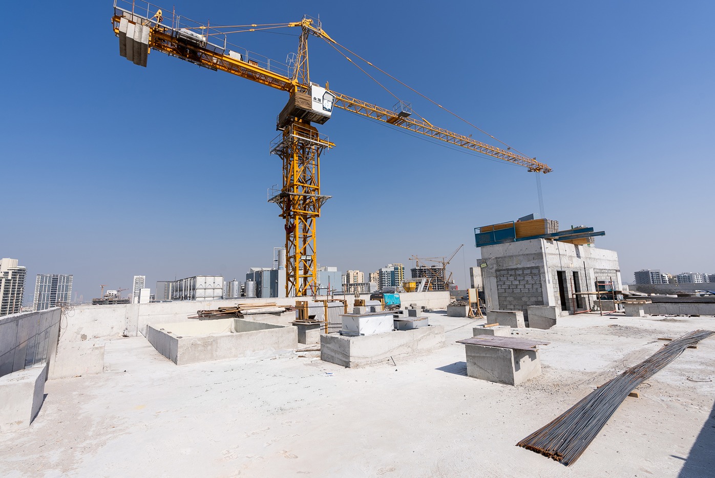 Pearl House By Imtiaz A construction site featuring a tall crane, concrete structures, and building materials under a clear blue sky.