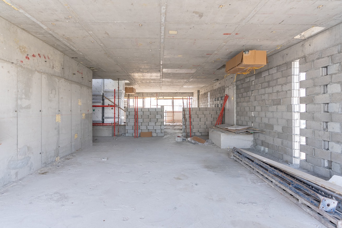 Pearl House By Imtiaz An unfinished construction site featuring exposed concrete walls, stacks of cinder blocks, and red scaffolding.