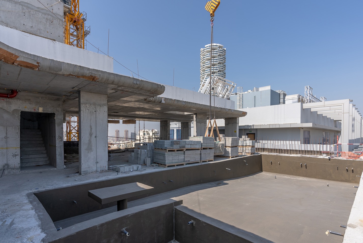Pearl House By Imtiaz Construction site featuring a concrete structure, scaffolding, and materials with a clear blue sky above.