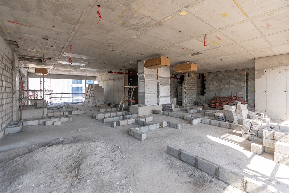 Pearl House By Imtiaz An empty construction site featuring gray concrete blocks, scaffolding, and unfinished walls under a concrete ceiling.