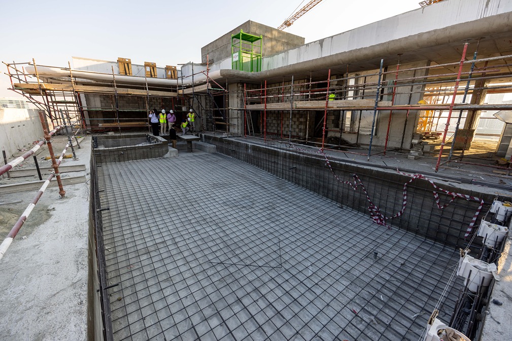 Pearl House By Imtiaz Construction site with scaffolding and workers, featuring concrete framework and a pool area being prepared.