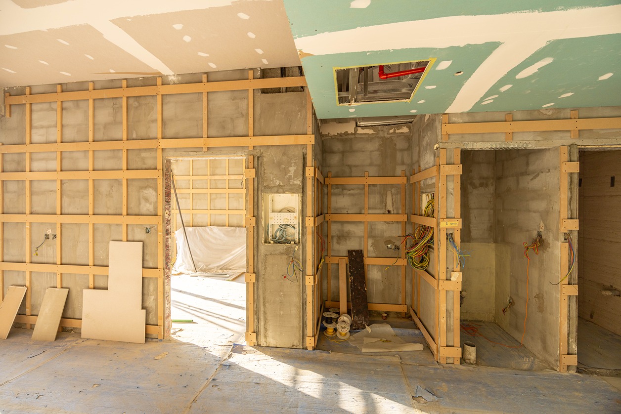 Pearl House By Imtiaz Construction site with framed walls, exposed wiring, and unfinished surfaces. Light shines through openings.