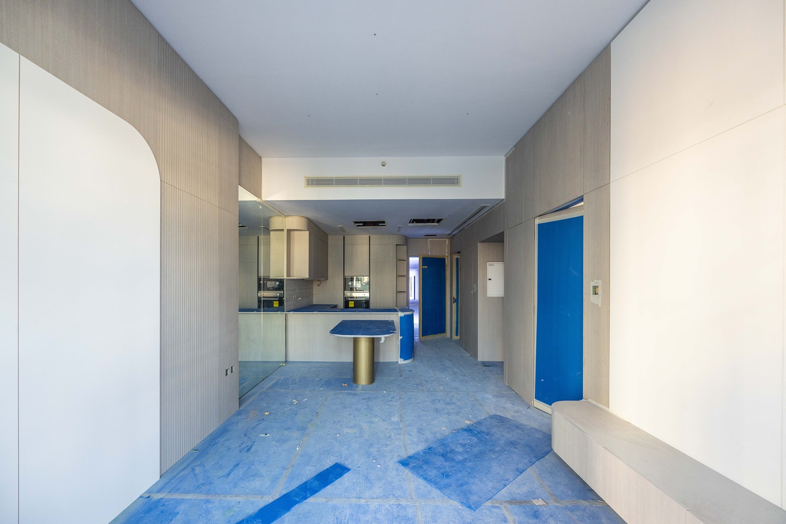 Pearl House By Imtiaz A modern kitchen area with light wood cabinets, blue accents, and a cluttered floor under construction.