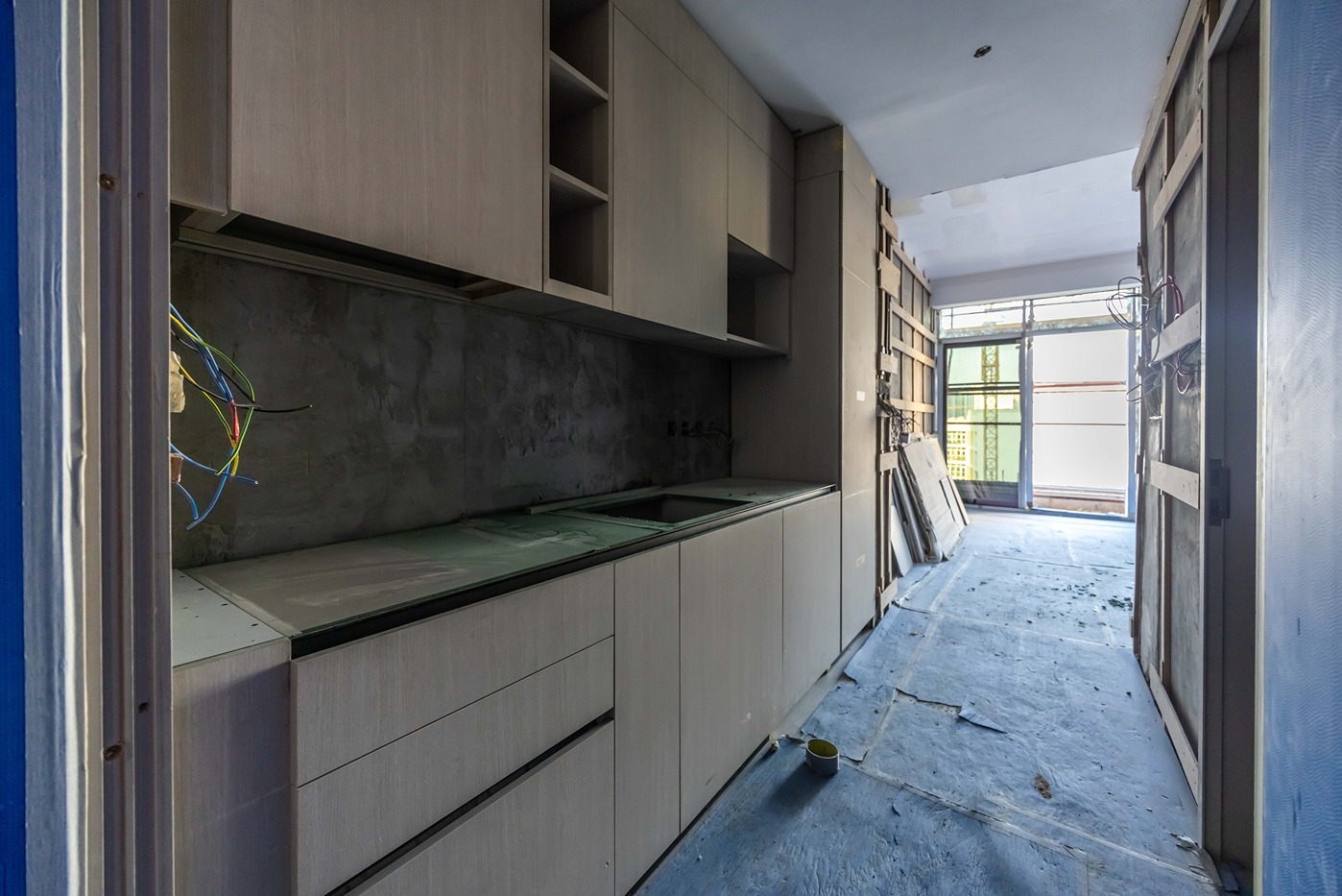 Pearl House By Imtiaz A partially constructed kitchen with built-in cabinets, an unfinished countertop, and exposed wiring.