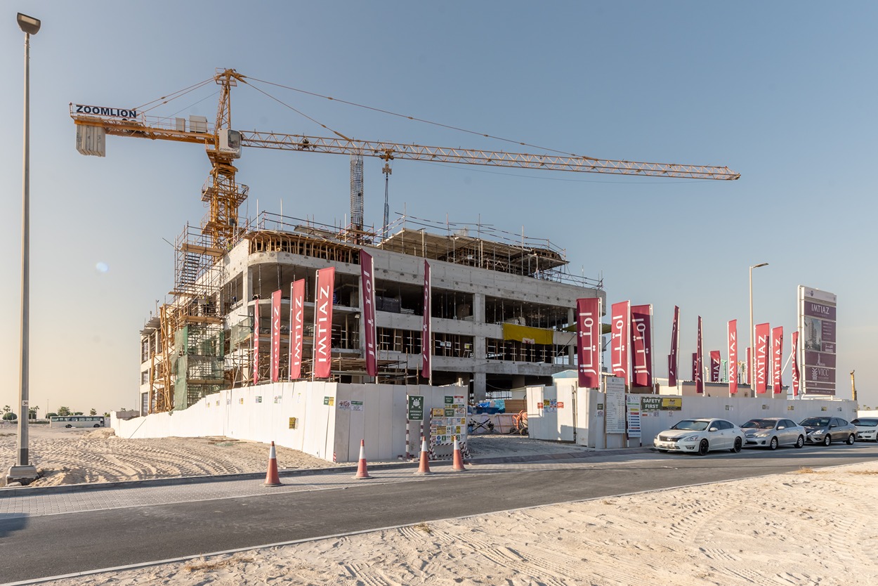 Beach Walk Residence A construction site featuring a partially built building with scaffolding, a crane, and promotional banners.