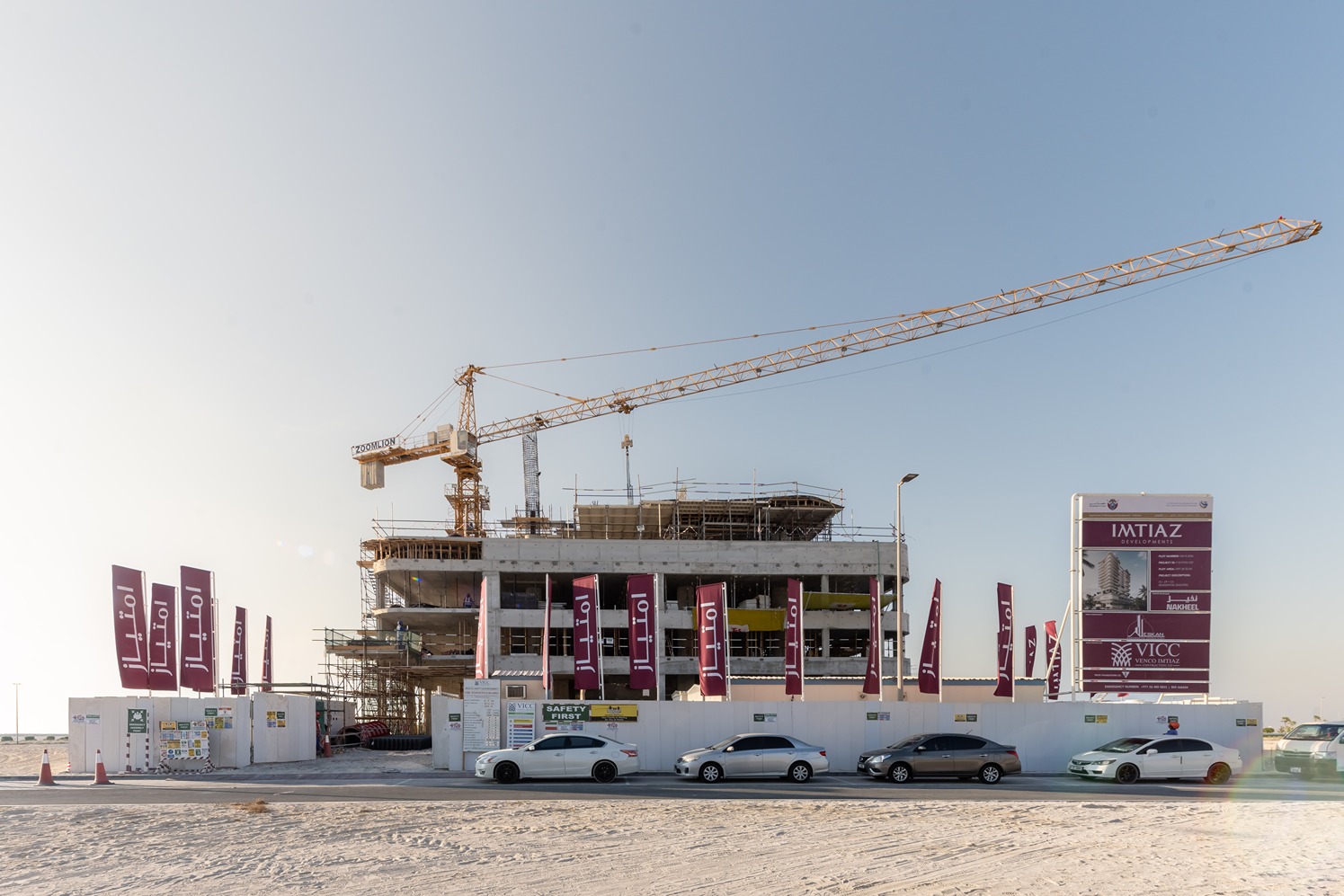 Beach Walk Residence Construction site with a crane, new building structure, and promotional banners on a clear day.