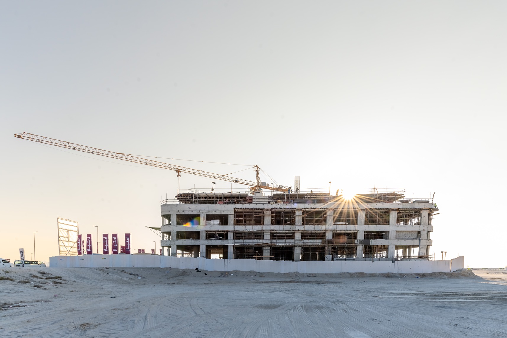 Beach Walk Residence A construction site featuring a partially built building with scaffolding and a crane, illuminated by sunset.