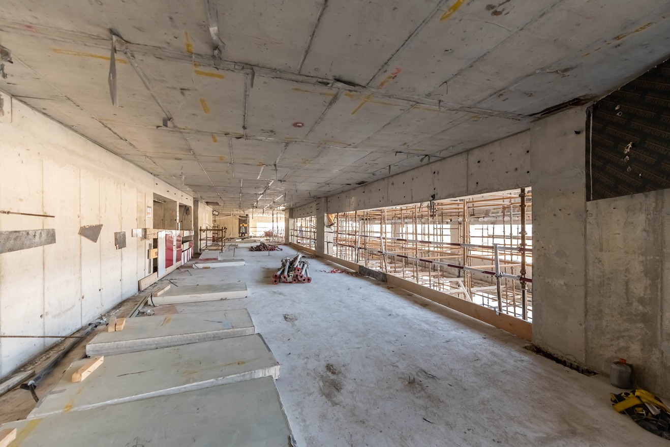 Beach Walk Residence An unfinished indoor space under construction, with concrete floors, scaffolding, and construction materials scattered around.