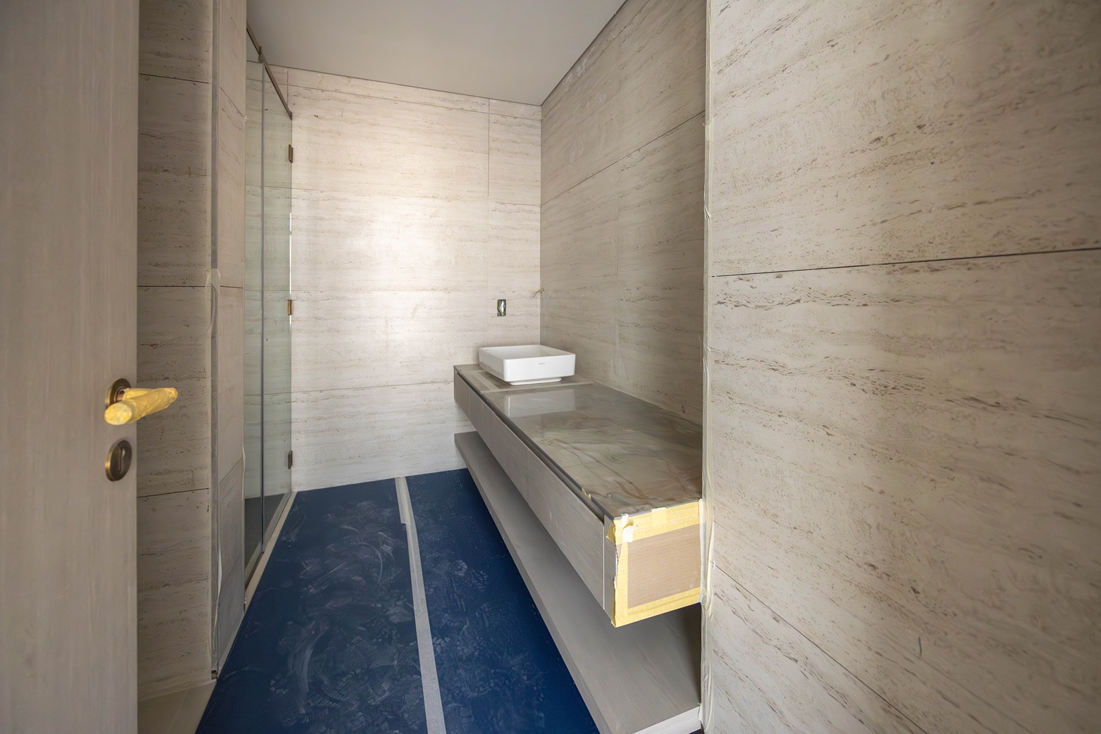 Pearl House By Imtiaz A modern, minimalist bathroom interior featuring a white sink, smooth walls, and a blue floor.