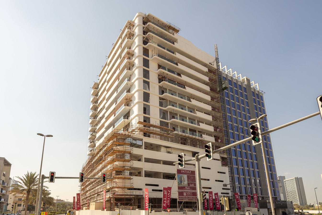 Pearl House By Imtiaz A partially constructed modern building with scaffolding, surrounded by palm trees and traffic lights.