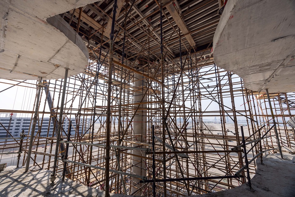 Beach Walk Residence A view of a construction site featuring a complex scaffolding structure surrounding a large concrete pillar.