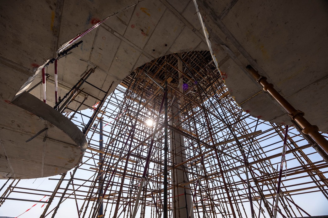 Beach Walk Residence View of scaffolding and concrete structure with sunlight shining through, creating an industrial atmosphere.