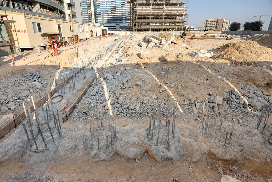 Cove Edition I By Imtiaz 1 Construction site featuring excavated land, rebar foundations, and nearby structural framework in an urban setting.