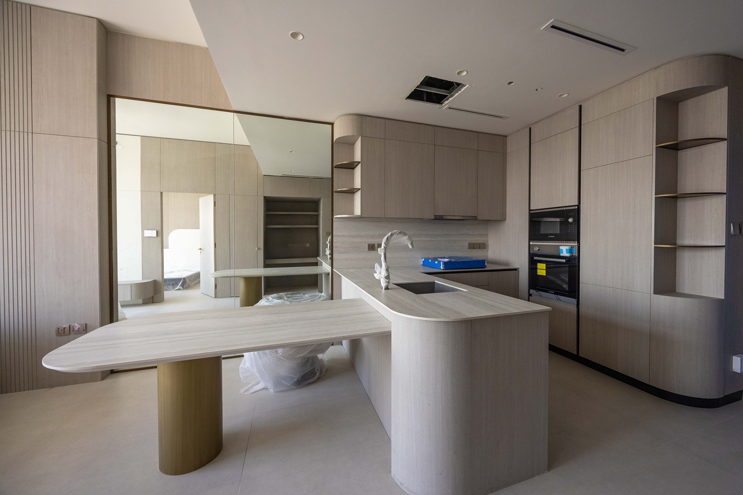 Pearl House By Imtiaz Modern kitchen featuring light wooden cabinets, a sleek countertop, and an island with a curved design.