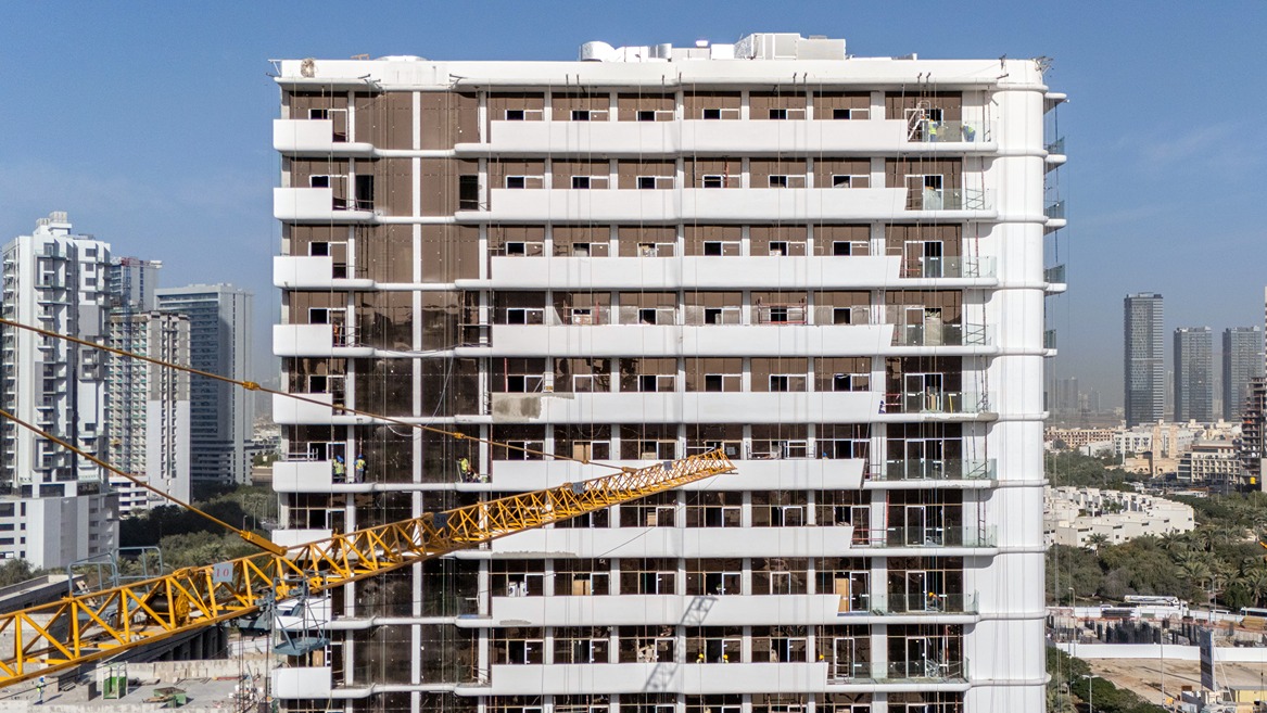 Pearl House By Imtiaz Construction workers are visible on a building facade with scaffolding and a crane operating nearby.