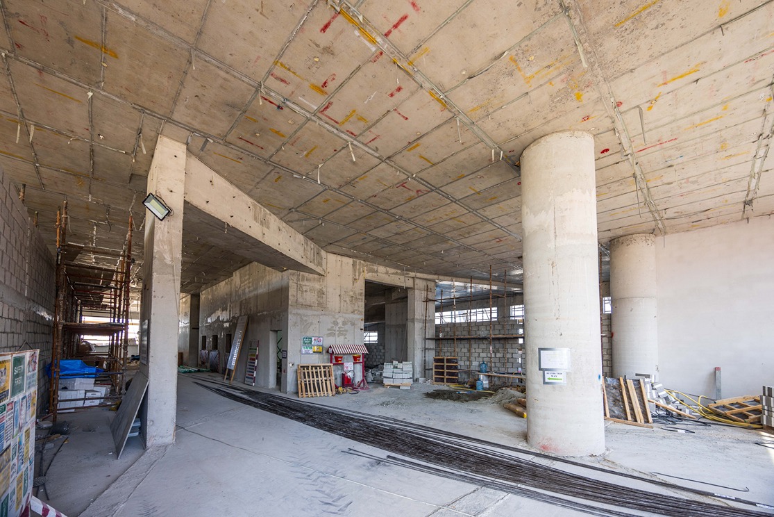 Beach Walk Residence A spacious, unfinished construction site featuring exposed concrete walls, columns, and scattered building materials.