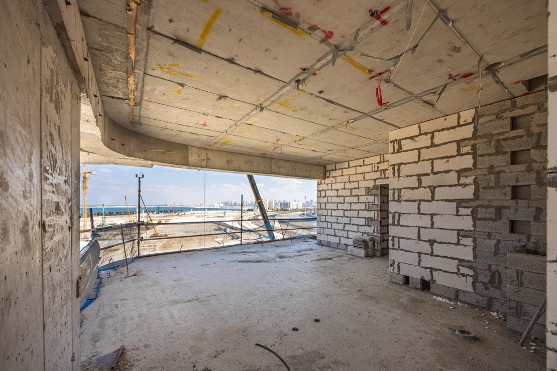 Beach Walk Residence An unfinished interior of a building with exposed walls, concrete flooring, and a view of a coastal city.