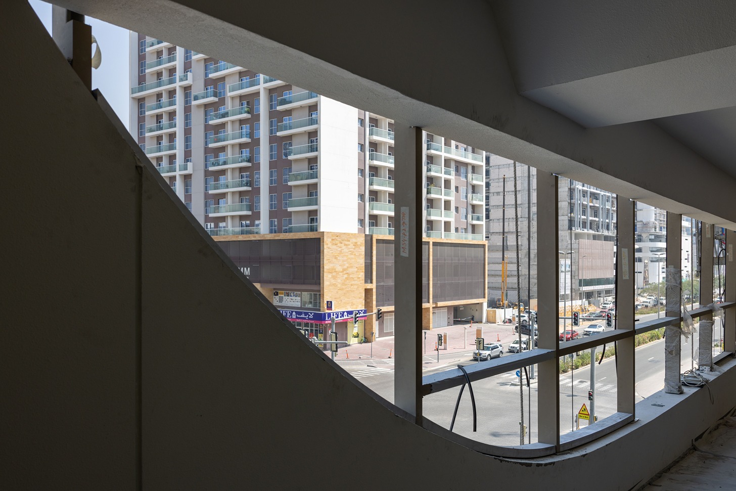 Pearl House By Imtiaz View from a building showcasing large windows, neighboring buildings, and a street with cars and pedestrians below.
