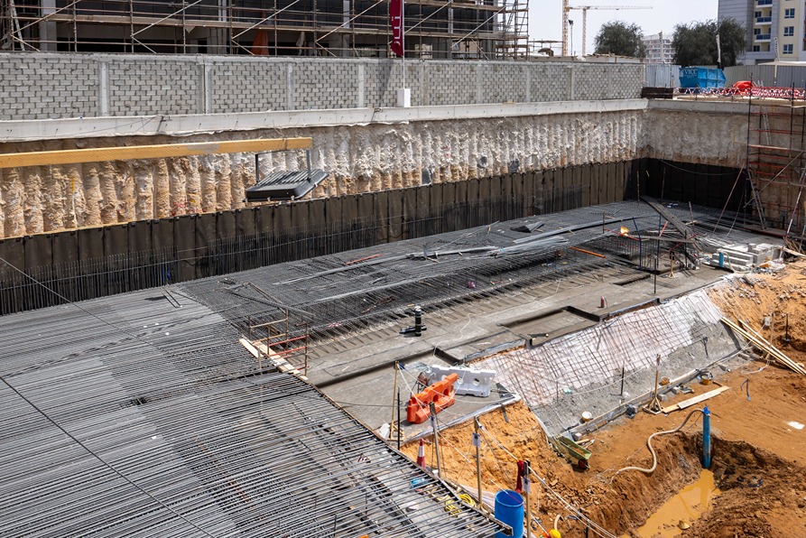 Cove Edition I By Imtiaz 1 Construction site showing a deep excavation with steel rebar, concrete foundation, and surrounding scaffolding.