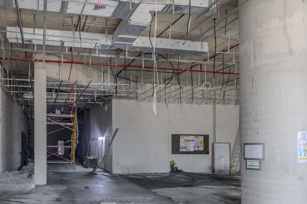 Beach Walk Residence A partially constructed interior space with exposed ceilings, scaffolding, and construction materials visible.