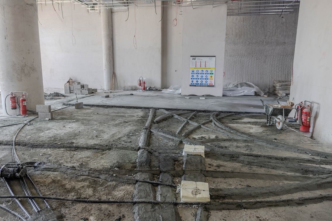 Beach Walk Residence A construction site interior featuring exposed floors, plumbing, fire extinguishers, and materials for ongoing work.