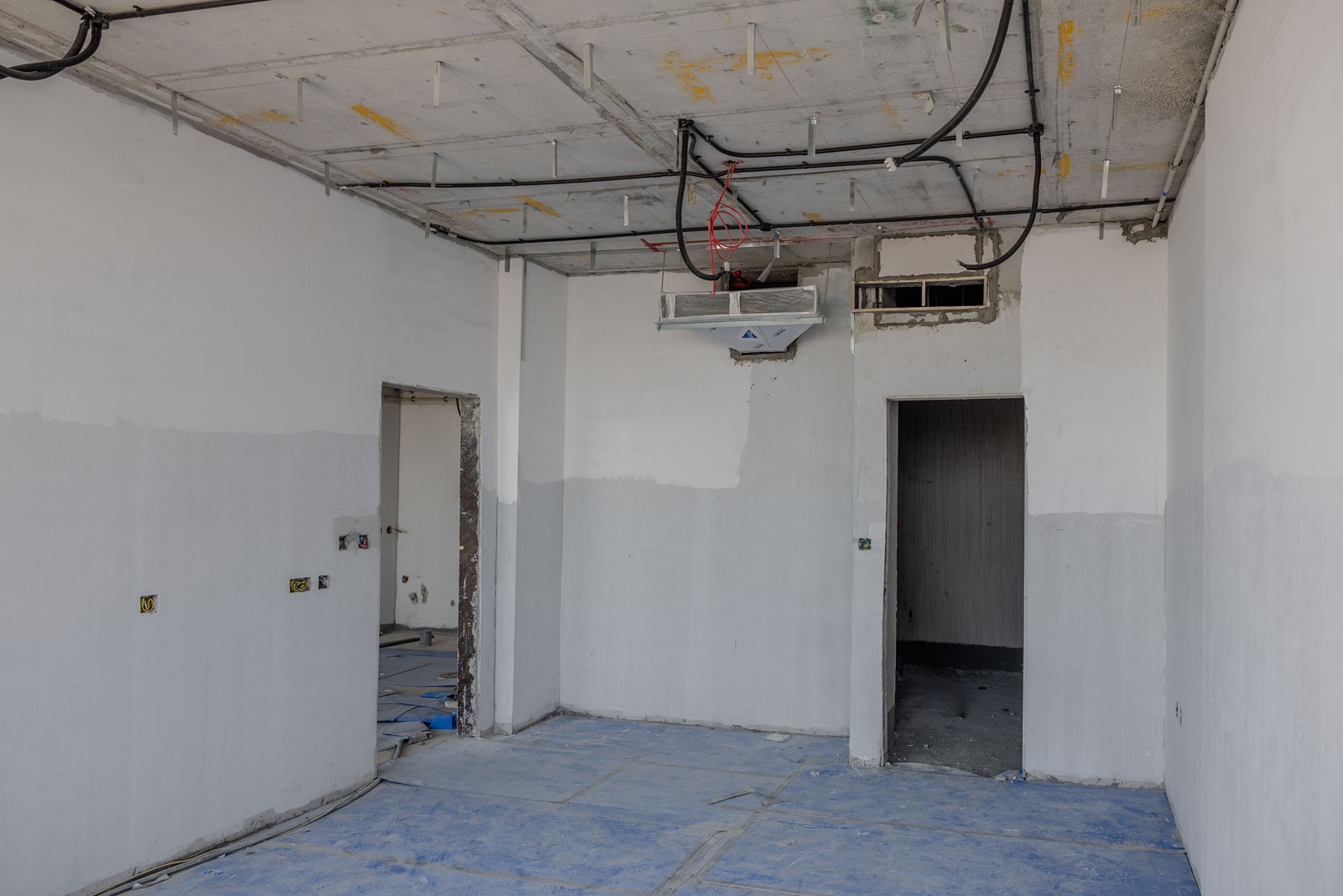 Beach Walk Residence An empty room with unfinished white walls, blue floor coverings, and an air conditioning unit on the ceiling.