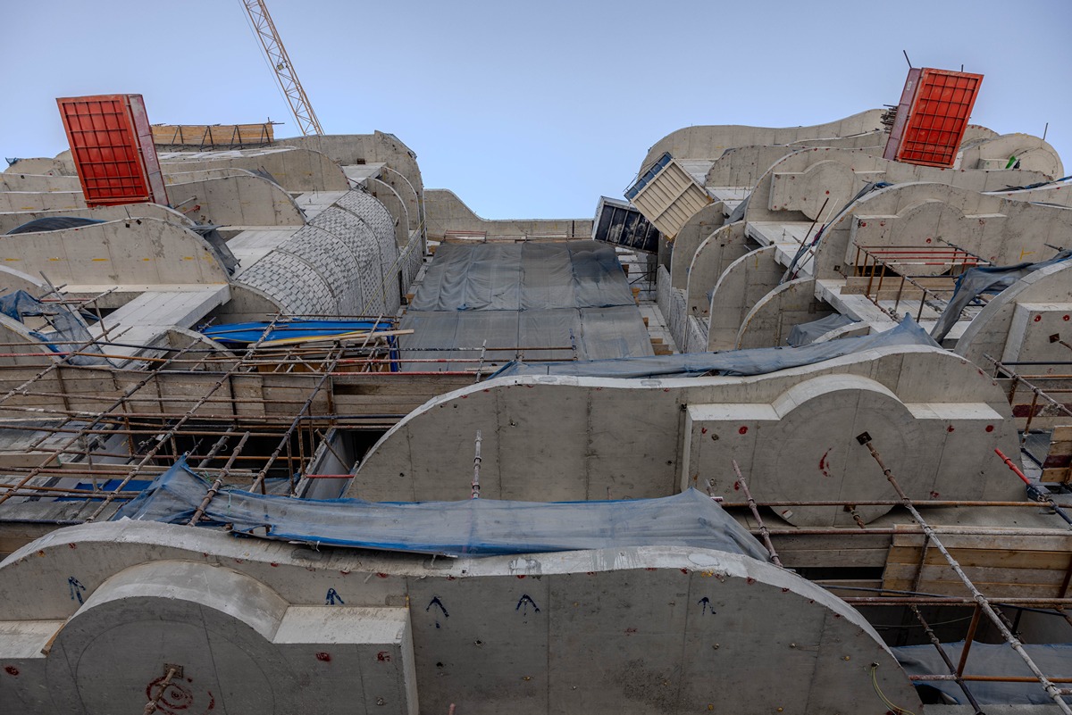 Beach Walk Residence Construction site featuring a partially completed building with scaffolding, concrete walls, and protective coverings.